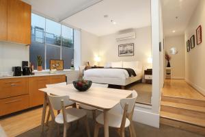 a kitchen and a bedroom with a bed and a table at StayCentral - Merigold on Collins in Melbourne