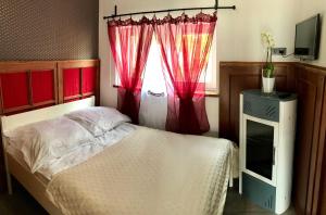 a bedroom with a bed with red curtains and a window at Marlin - pokoje nad morzem in Bobolin