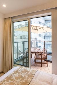 a bedroom with a bed and a balcony with a table at Hotel SAILS in Tokyo