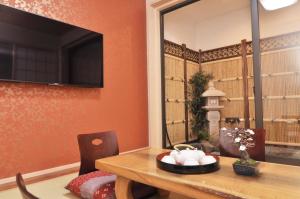 a dining room with a table and a television on a wall at Shirakabanoyado - Osakajo in Osaka