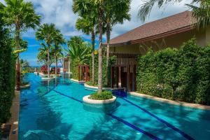 a swimming pool with blue water and palm trees at Mandarava Resort and Spa, Karon Beach - SHA Extra Plus in Karon Beach