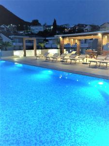 een groot zwembad met stoelen en een gebouw bij Apartment Sun Village Goran in Herceg-Novi