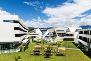 a large white building with a yard with tables and chairs at Thermenhotel Karawankenhof in Villach