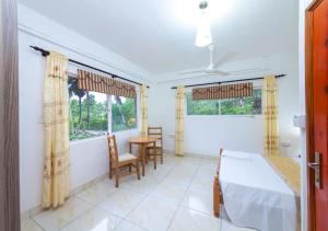 a bedroom with a bed and a table and two windows at Chez Julie in Anse Boileau