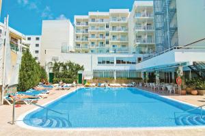 une piscine avec des chaises longues et un grand bâtiment dans l'établissement BLUESEA Piscis - Adults Only, à Port d'Alcúdia