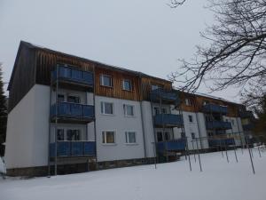 クアオルト・オーバーヴィーゼンタールにあるFerienwohnung Fichtelbergの雪面の青いバルコニー付きの大きな建物