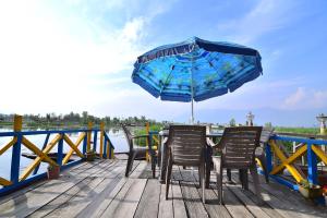 una mesa con 2 sillas y una sombrilla en un muelle en Golden Hopes Group of Houseboats, en Srinagar