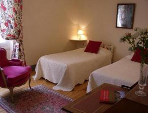 a room with two beds and a chair and a table at Appartement du Château du Grand Bouchet in Ballan-Miré