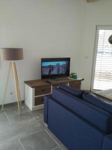 a living room with a blue couch and a tv at Ferienhaus Pfaffensee in Harthausen