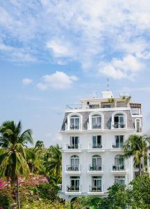 a white building with palm trees in front of it at La Marina Boutique Hotel & Spa in Mui Ne