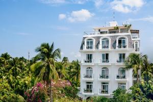 a white building with palm trees and flowers at La Marina Boutique Hotel & Spa in Mui Ne