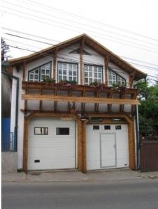 a house with two garage doors and a balcony at Pensiunea Ana Maria in Târgu-Mureş