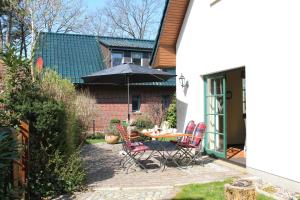 a patio with a table and chairs with an umbrella at Ferienhaus "Sanddüne No.19" in Boltenhagen