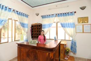 a woman standing at a desk in a room with windows at Khách sạn Cà Ná in Phan Rang