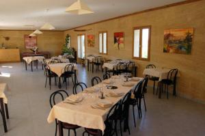 une salle à manger avec des tables, des chaises et un tissu de table blanc dans l'établissement Le Clos Boisé, à Théziers