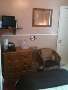 a bedroom with a dresser and a chair and a mirror at Molyneux Guesthouse in Weymouth