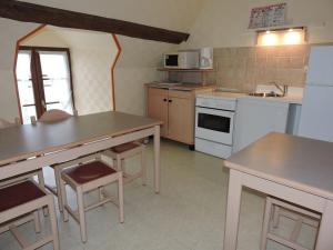 una cocina con electrodomésticos blancos y mesas y sillas de madera. en Les Berges, en Mareuil-sur-Cher