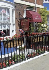 a black fence with flowers and a building at Molyneux Guesthouse in Weymouth