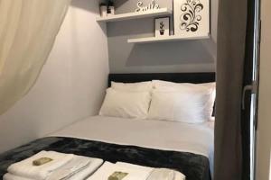 a small bedroom with a bed with white sheets and pillows at Cozy studio 50m from sea in Athens