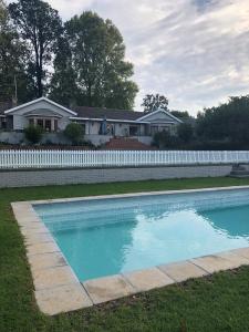 a swimming pool in front of a white fence at Notting Hill Lodge in Balgowan