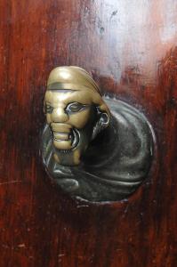 a gold door knocker of a face on a wooden door at B&B Cà Del Modena in Venice