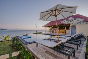 a deck with chairs and an umbrella and a pool at Lembongan Seaview in Nusa Lembongan