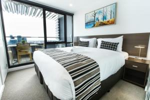 a bedroom with a large bed and a balcony at Spencer Street Apartments in Melbourne