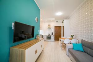 a living room with a couch and a tv on a wall at Apartamenty Roztocze in Zwierzyniec