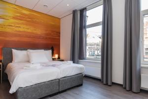 um quarto com uma cama com um quadro na parede em City2Beach Hotel em Vlissingen