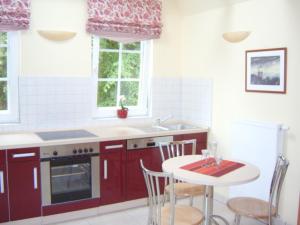 a kitchen with red cabinets and a table with chairs at Aalkoje Ostseebad Wustrow in Wustrow