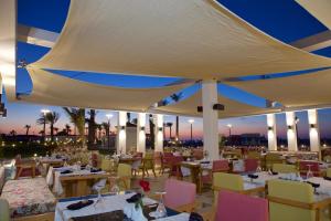 a restaurant with tables and chairs and a white umbrella at Rixos Alamein - Full Board Plus in El Alamein