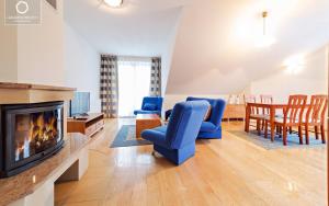 sala de estar con sillas azules y chimenea en Wonder Home - Apartamenty z balkonami w centrum Karpacza - blisko szlaków i parku miejskiego z zewnętrzną siłownią en Karpacz