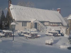 a building covered in snow with picnic tables in front of it at Compasses Inn in Tisbury