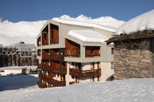 un immeuble dans la neige avec des montagnes enneigées dans l'établissement Résidence Odalys Le Hameau du Borsat, à Tignes