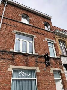 un bâtiment en briques avec des fenêtres et un panneau sur celui-ci dans l'établissement Elysian, à Ypres