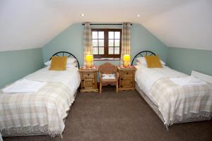 two beds in a room with a desk and a window at The Old Cart House in Salton