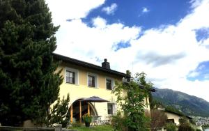 ein gelbes Haus mit einem Regenschirm davor in der Unterkunft Greina in Celerina