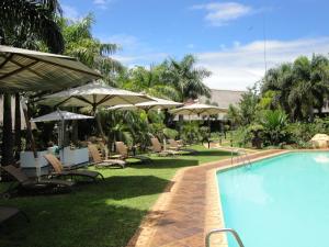 una piscina con sillas y sombrillas junto a un complejo en Summerfield Botanical Garden & Exclusive Resort en Matsapha