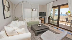 sala de estar con muebles blancos y TV en Marina del Castillo 305 en Manilva