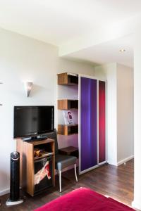 a living room with a tv and a colorful closet at Auszeit Hotel Düsseldorf - das Frühstückshotel - Partner of SORAT Hotels in Düsseldorf