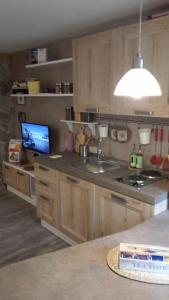 a kitchen with wooden cabinets and a sink and a television at Casetta next to the Creek Dino Buzzati in Belluno