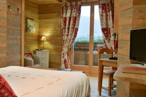 a bedroom with a bed and a desk and a window at Hotel-Spa Le Morillon Charme & Caractère in Morillon