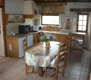 une cuisine avec une table et un vase de fleurs. dans l'établissement Gîte au cœur du Lot, la maison de Pauline, à Lentillac du Causse