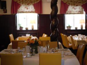 a dining room with tables and chairs with flowers on them at Hotel Restaurant Jägerhof in Düren - Eifel