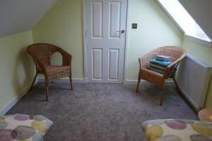 a attic room with two chairs and a door at The Den , Sengera in Inverness
