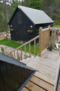 a wooden ramp leading to a black building with a fence at The Den , Sengera in Inverness