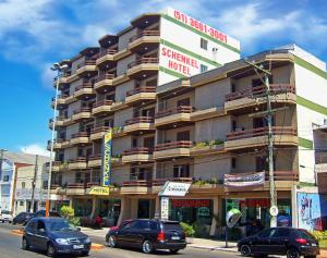 um grande edifício com carros estacionados em frente em Schenkel Hotel em Tramandaí