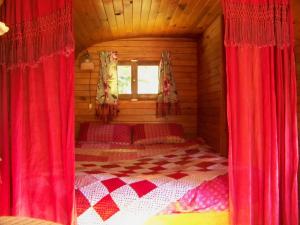 a bedroom with red curtains and a bed in a cabin at la boutique de laurence in Ségrie-Fontaine