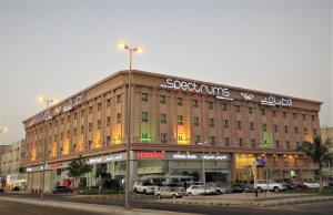 un grand bâtiment avec des voitures garées dans un parking dans l'établissement Spectrums Residence Jeddah, à Djeddah