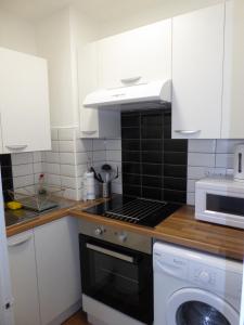 a kitchen with a stove top oven next to a microwave at Soft & Bright in Thornton Heath